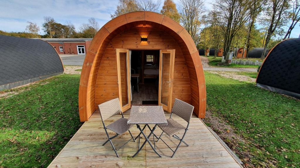 uma pequena estrutura de madeira com duas cadeiras e uma mesa em 09 Premium Camping Pod em Silberstedt