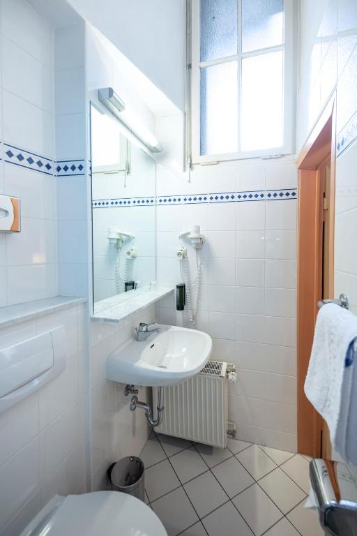 a white bathroom with a sink and a toilet at ACHAT Sternhotel Bonn in Bonn