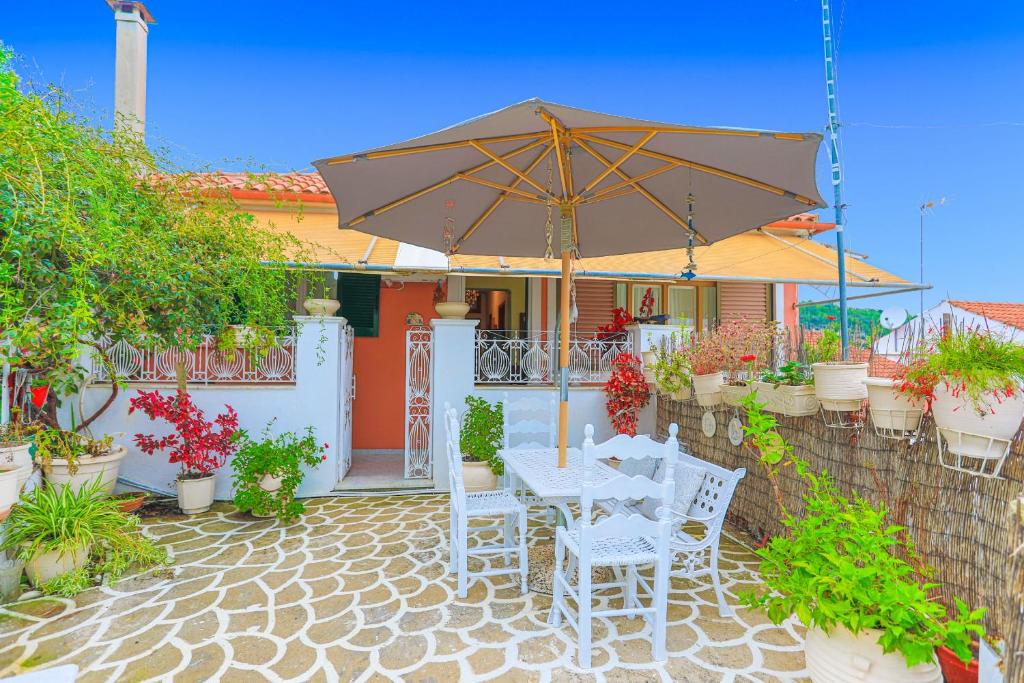 eine Terrasse mit einem Tisch, Stühlen und einem Sonnenschirm in der Unterkunft Agathi House in Gaios