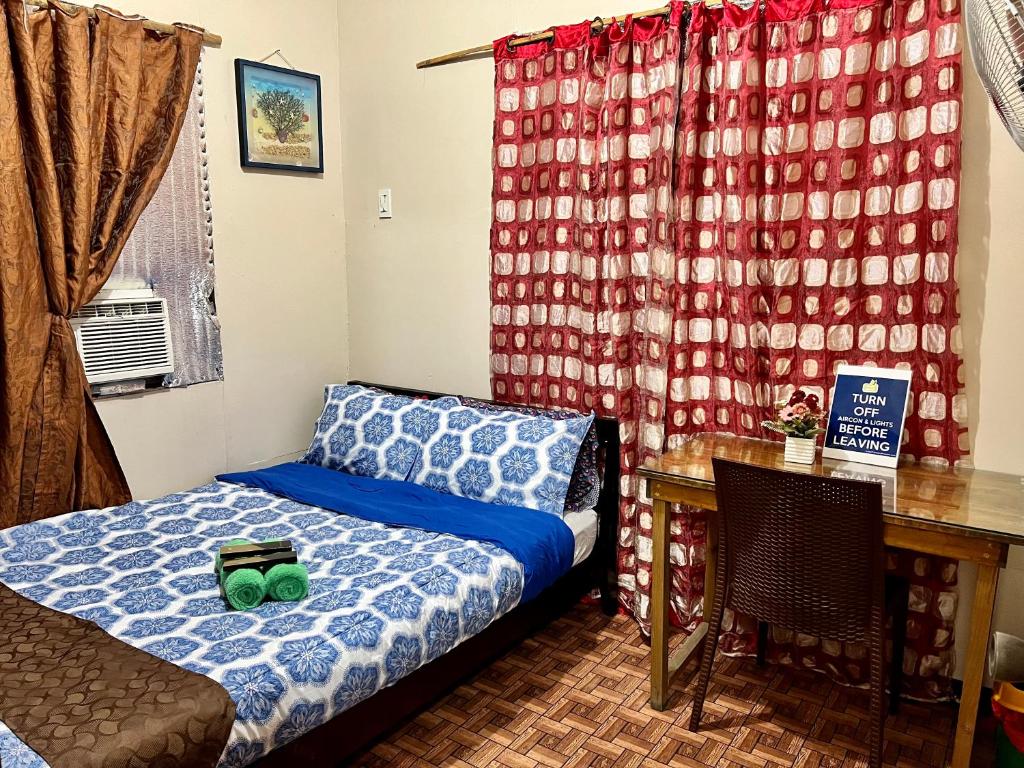 a bedroom with a bed and a desk and a table at May’s Home Away from Home in Cebu City