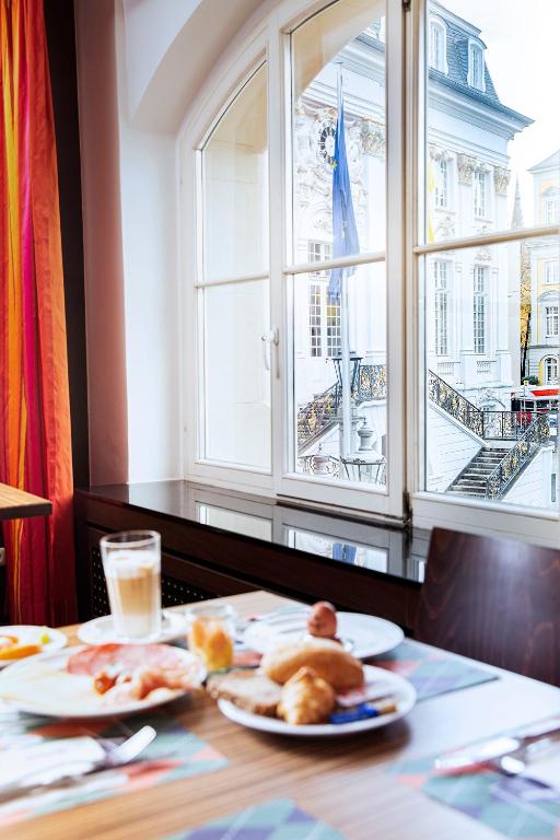 a table with two plates of food and a window at ACHAT Sternhotel Bonn in Bonn