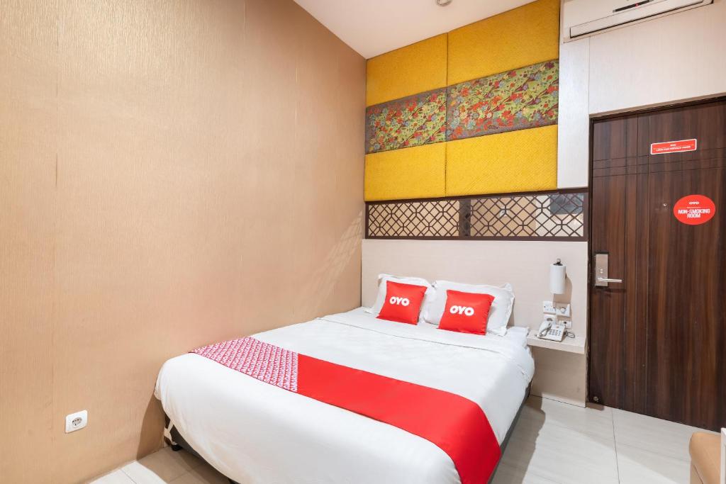 a bedroom with a bed with two red pillows at SUPER OYO Flagship 91963 Series Style Hotel in Putat-wetan