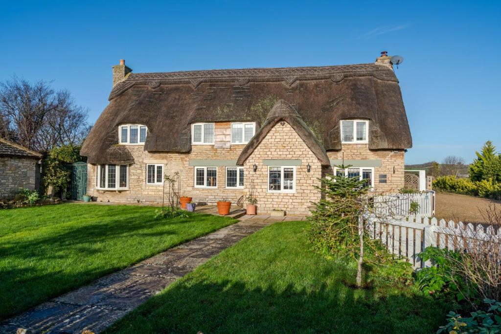 an old house with a thatched roof at The Thatch House in Woolstone