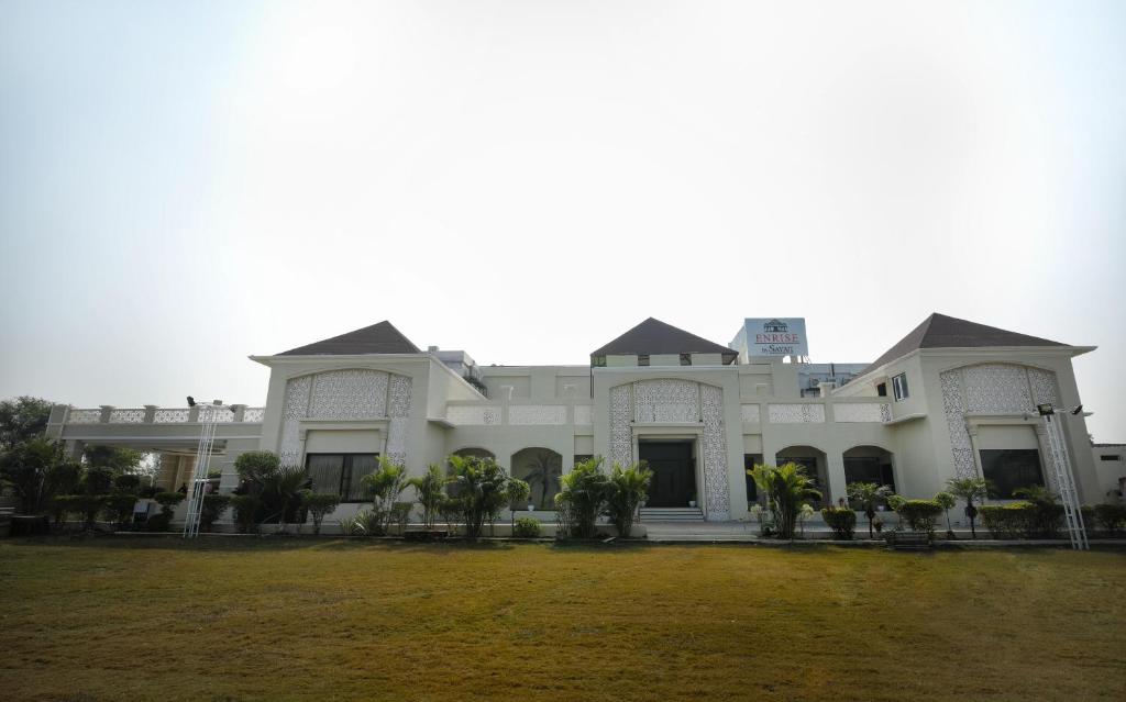 a large white building with a grass yard at Enrise by Sayaji Rewa in Rewa