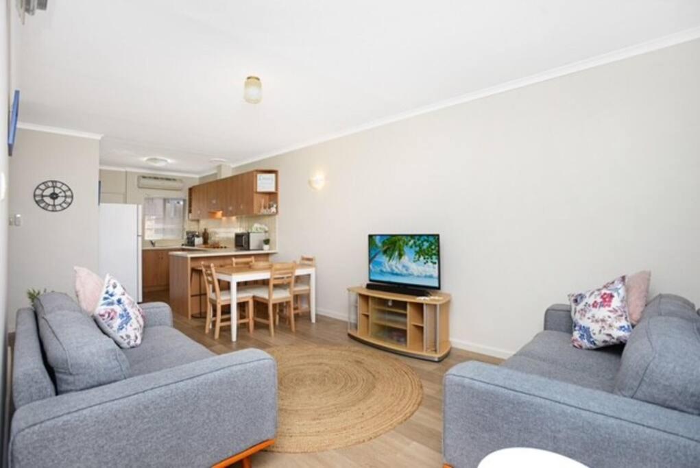 a living room with two couches and a kitchen at Victor Seaside Villa in Victor Harbor