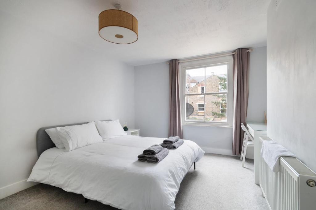 a white bedroom with a bed and a window at 1 bed Clapham Junction apartment in London