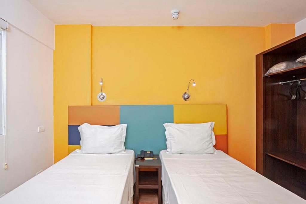 two beds in a room with yellow and blue at Tri Hotel Balneario Camboriu in Balneário Camboriú