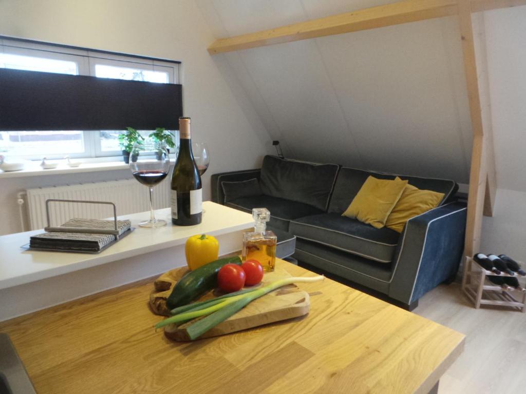 Sala de estar con mesa, botella de vino y sofá en Top appartement Short Stay in mooie omgeving Kortenhoef. en Kortenhoef