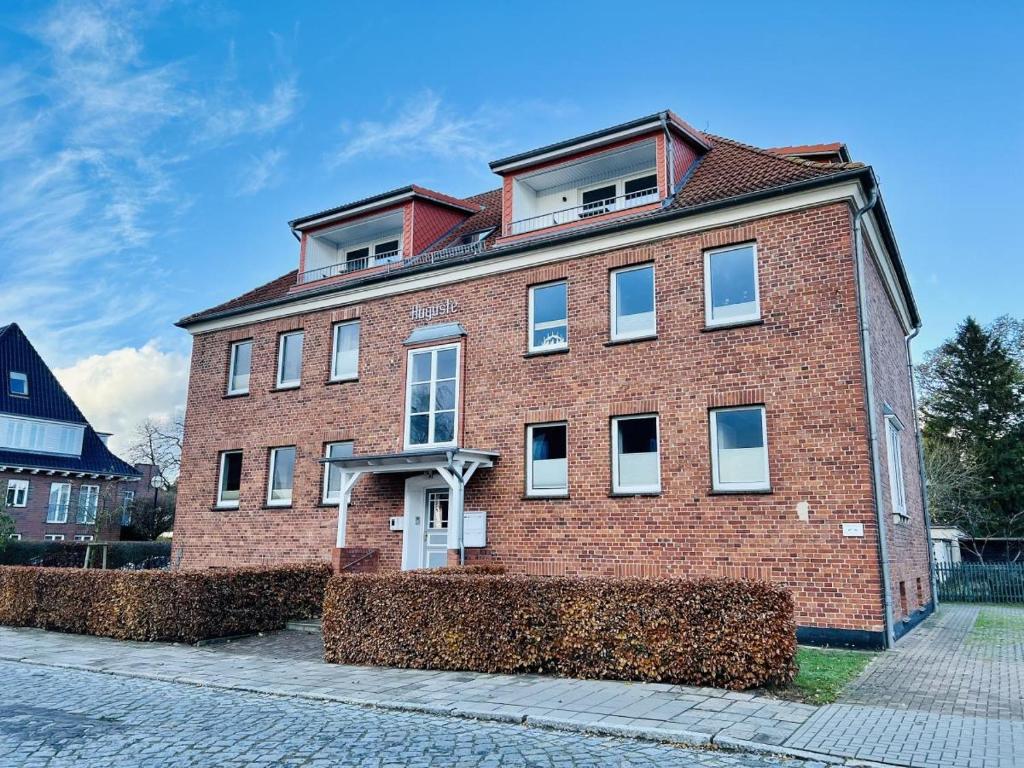 a red brick building with windows on a street at Haus Auguste, Strandlaeufer in Warnemünde