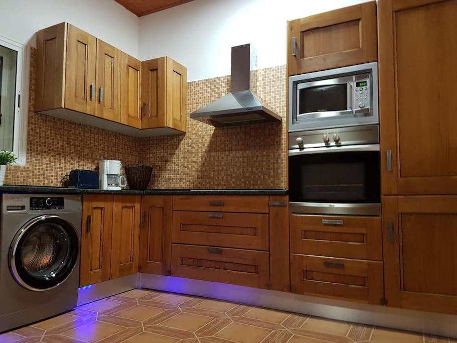 a kitchen with wooden cabinets and a washer and a microwave at Apartamento rural zona céntrica isla in Puerto del Rosario