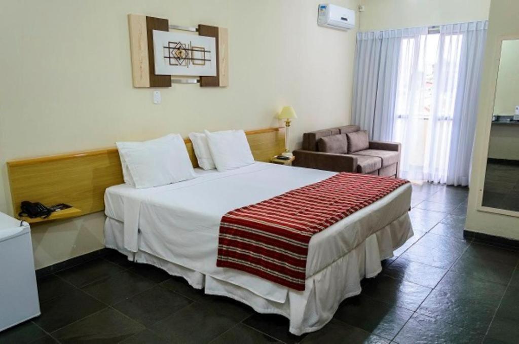 a hotel room with a large bed and a chair at Bravo Suites São Carlos in São Carlos