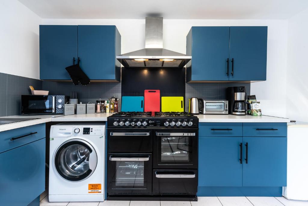 une cuisine avec des armoires bleues et un lave-linge dans l'établissement Jesouth Homey 5 Bedrooms 9 Beds - Contractors - Leisure - Central Location, à Hull