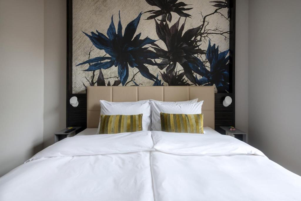 una camera da letto con un letto bianco e un dipinto sul muro di Numa Prague Poise a Praga