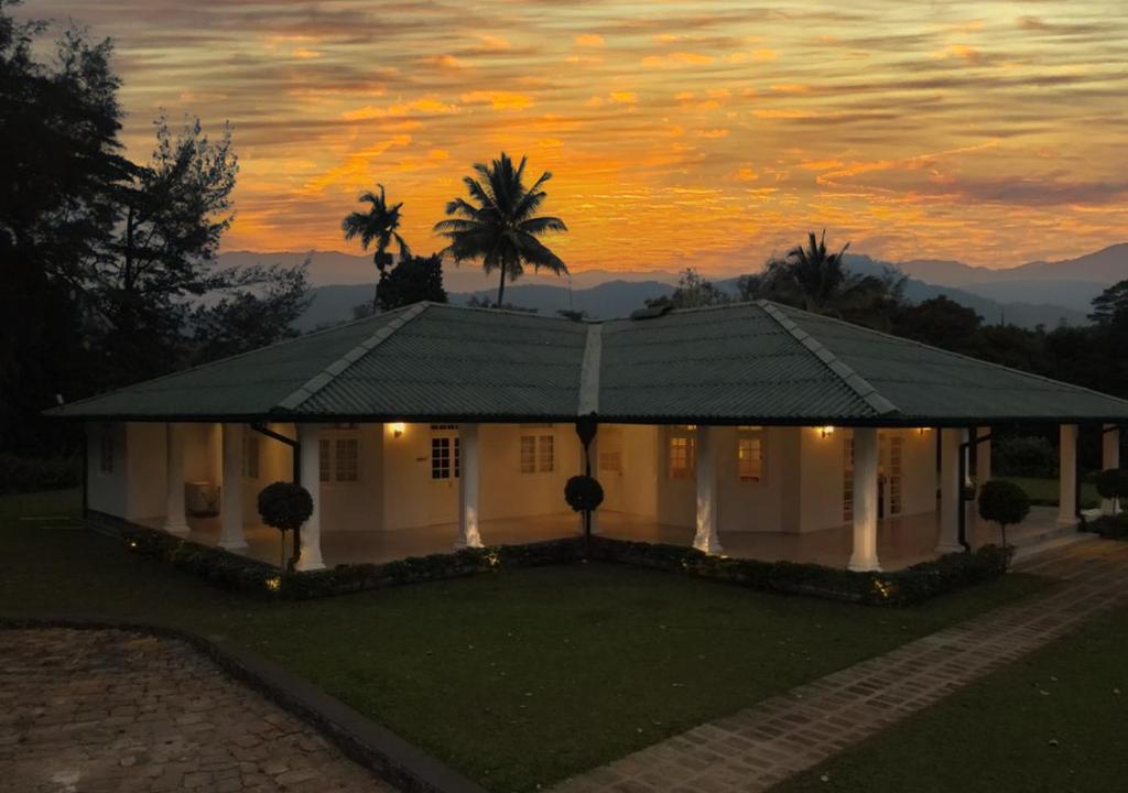 a white house with a palm tree and a sunset at The Estate 1920 in Pelmadulla