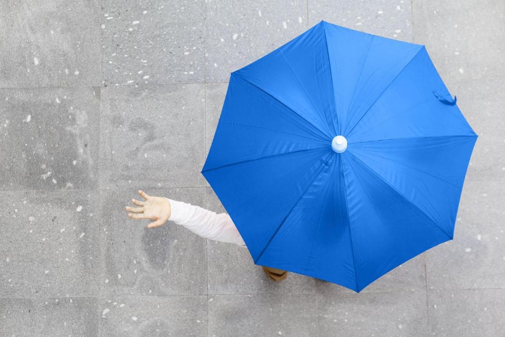 a person holding a blue umbrella in the rain at Holiday Inn Express Chennai OMR Thoraipakkam by IHG in Chennai