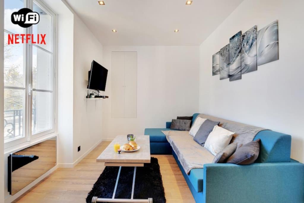 een woonkamer met een blauwe bank en een tafel bij Appartement 4 personnes aux Portes de Paris in Saint-Denis