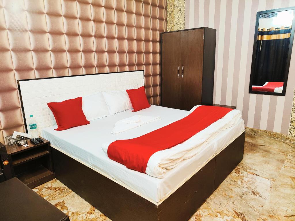 a bedroom with a bed with red and white pillows at Hotel kingsman in Rudrapur