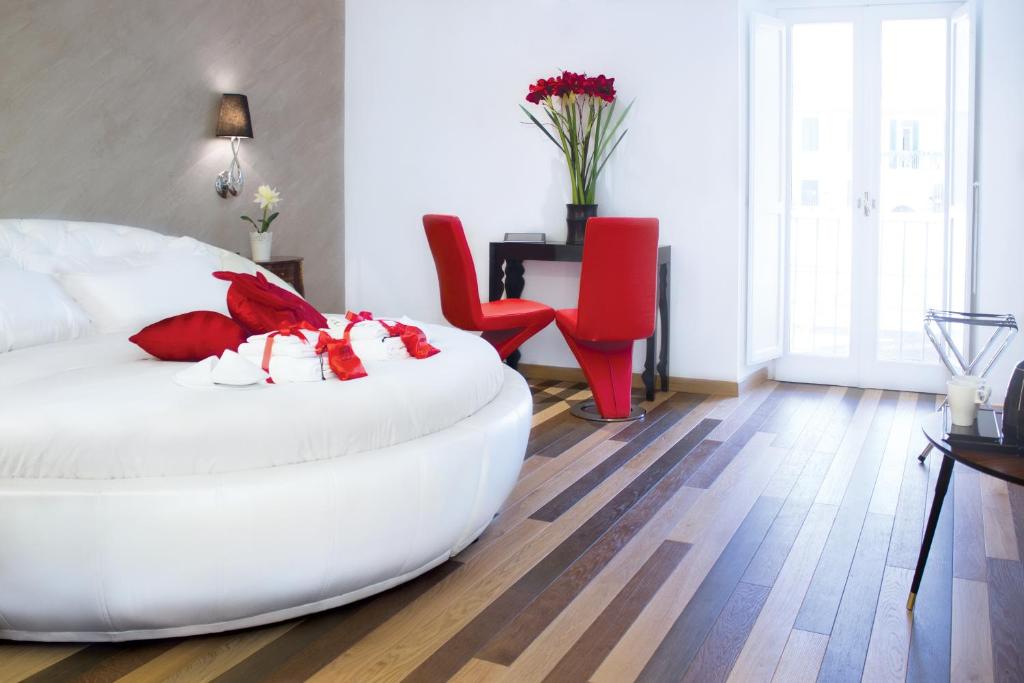1 dormitorio con 1 cama blanca grande y sillas rojas en Hub Navona, en Roma