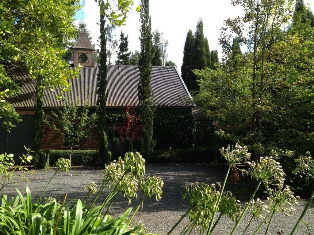 a garden with a building with a clock tower at Southdown Stable in Bowral