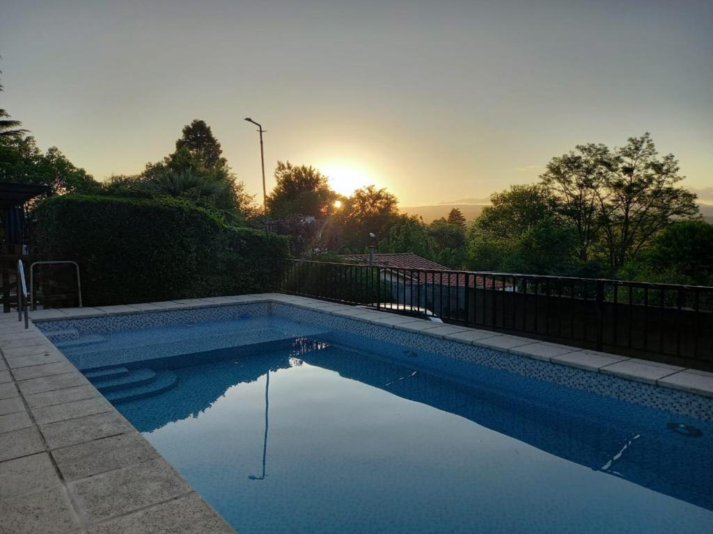 una piscina en un patio con la puesta de sol en el fondo en Casa Familiar Villa Carlos Paz en Villa Carlos Paz