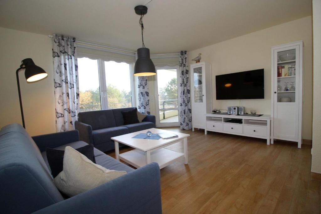 een woonkamer met een blauwe bank en een tv bij Kurpark-Residenz 108 in Döse