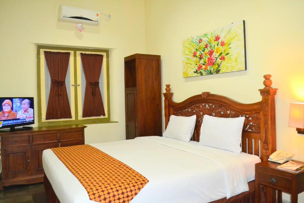 ein Schlafzimmer mit einem Bett und einem TV in der Unterkunft The Kresna Hotel in Yogyakarta