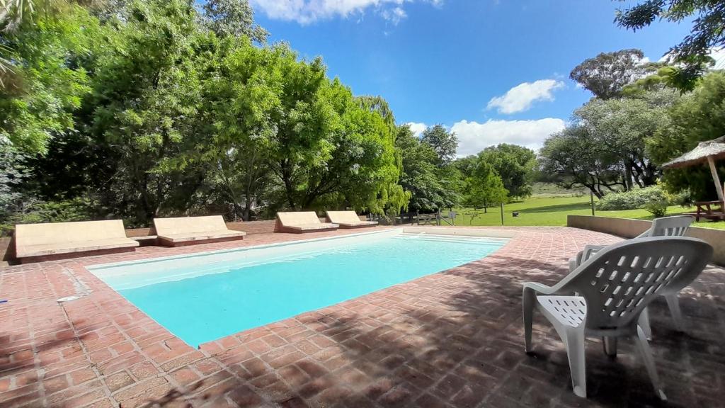 a swimming pool with two chairs and a table and a chair at Cabañas Las Dinas in Tandil