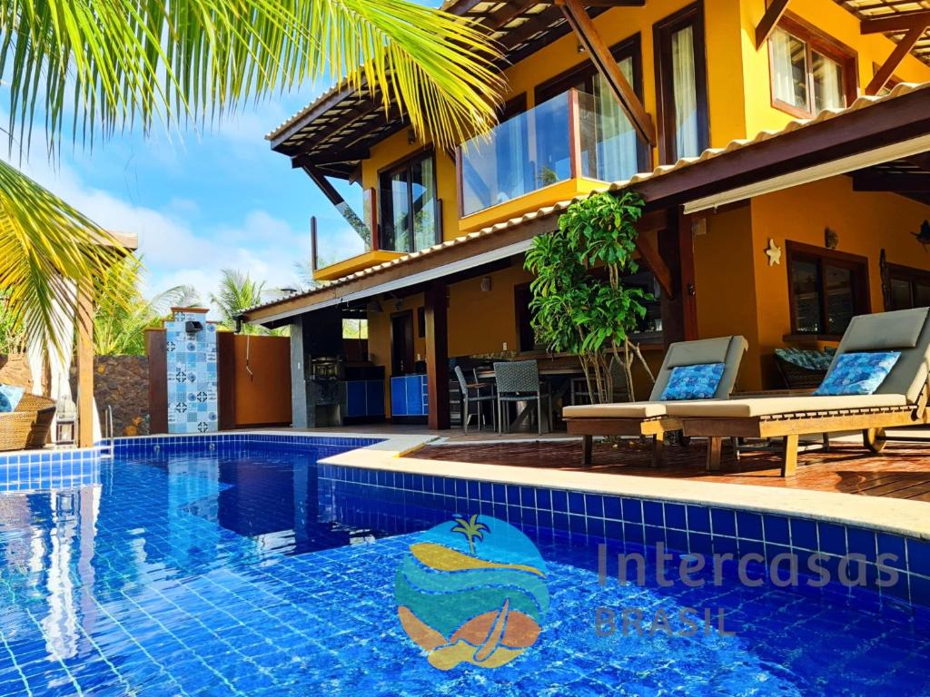 a swimming pool in front of a house at Villa Bora Bora - Frente mar, Praia do Forte in Praia do Forte