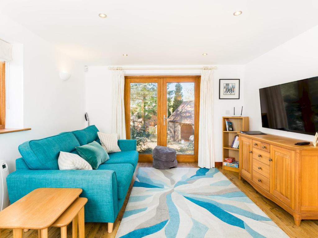 sala de estar con sofá azul y TV en Pass the Keys Rural Retreat in Rowington, Warwickshire, en Warwick