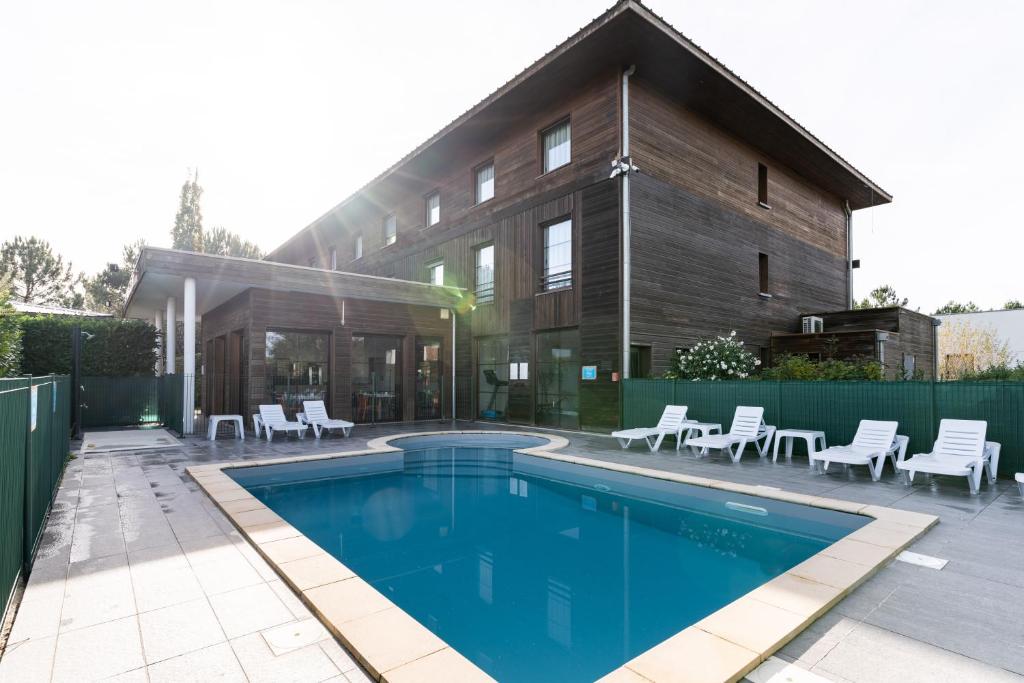 a house with a swimming pool in front of a house at All Suites Le Teich – Bassin d’Arcachon in Le Teich
