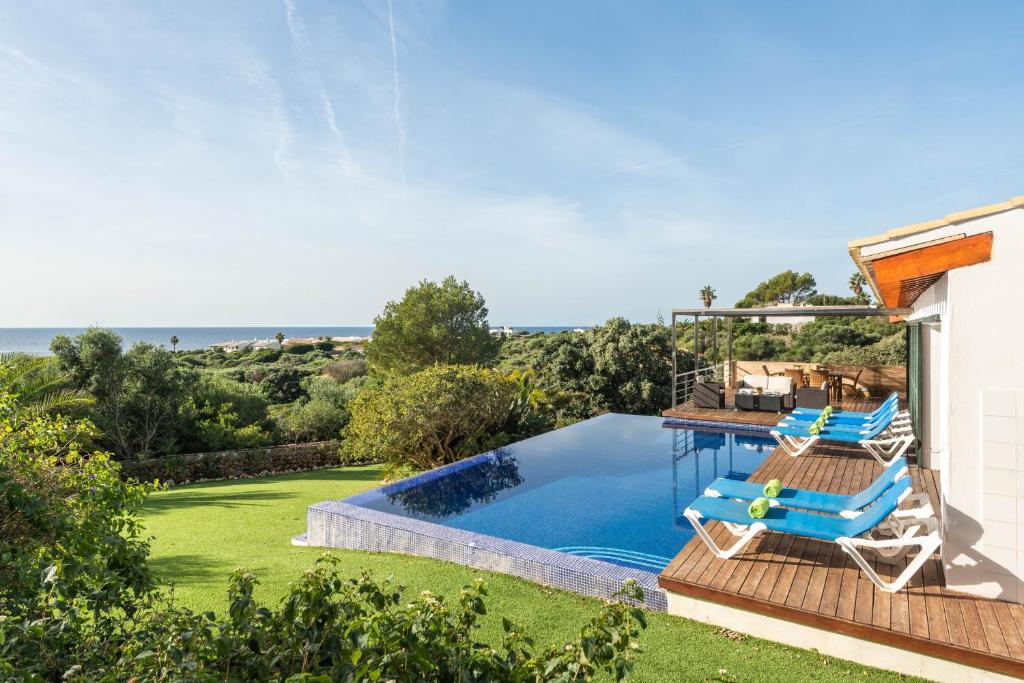 a house with a swimming pool and two lounge chairs at Villa Iris Torret by Escape Home in Sant Lluis