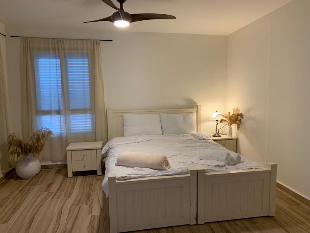 um quarto com uma grande cama branca e uma ventoinha de tecto em צימר מול פרדס 