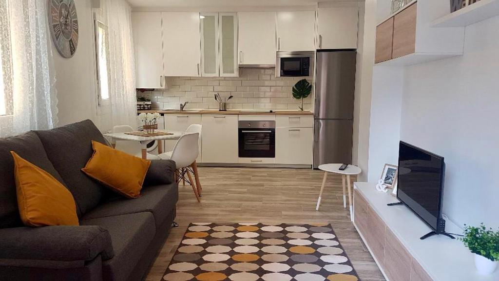 a living room with a couch and a kitchen at Apartamento La Plaza in Onís