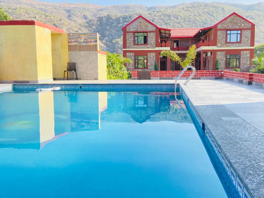 a house with a swimming pool in front of a house at Pushkar Retreat Resort - The Nature and Mountain View Resort ,Pushkar in Pushkar