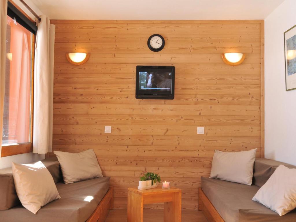 - un salon avec deux canapés et une télévision sur un mur en bois dans l'établissement Studio rénové au pied des pistes, balcon, pour 4 personnes - FR-1-181-2097, à La Plagne Tarentaise