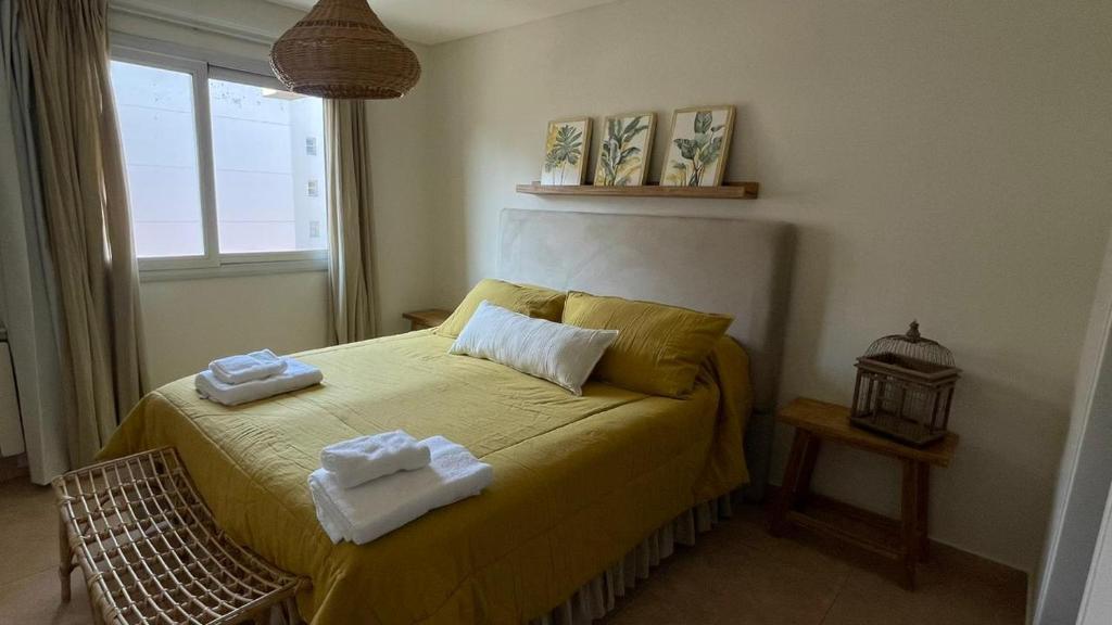 Un dormitorio con una cama amarilla con toallas. en Santiago Plaza Departamento Microcentro Premium en Salta