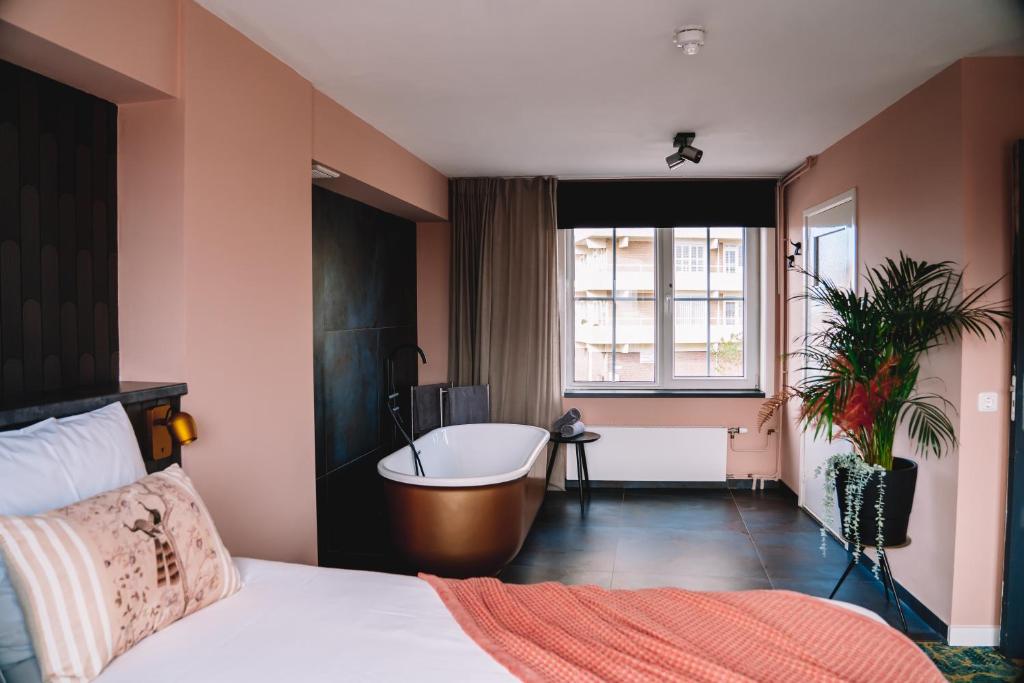 a bedroom with a bed and a tub and a window at Boutique Lodge Zandvoort in Zandvoort
