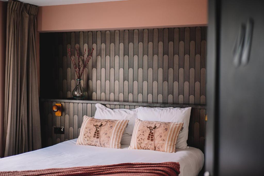 een slaapkamer met een groot bed met witte lakens en kussens bij Boutique Lodge Zandvoort in Zandvoort