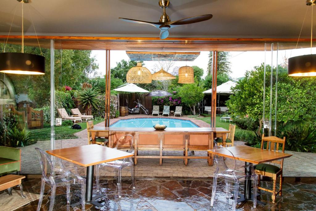 a patio with a pool and tables and chairs at La Pension Guest House in Oudtshoorn
