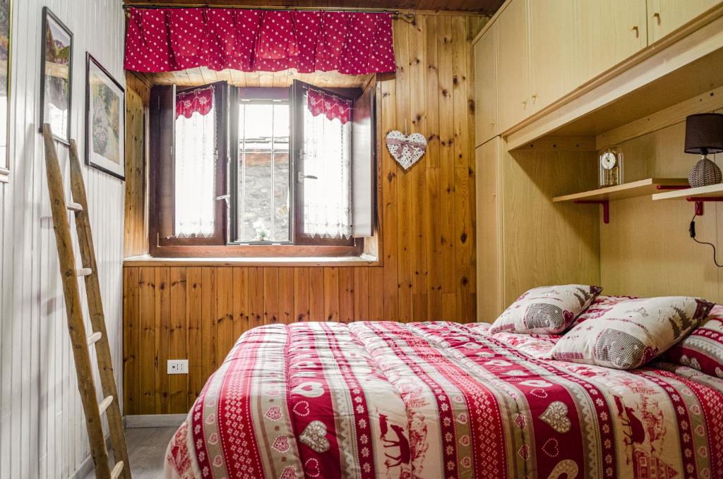 a bedroom with a bed and a window and a ladder at Maison Rhémy - Relax e montagne in Saint-Rhémy-en-bosses