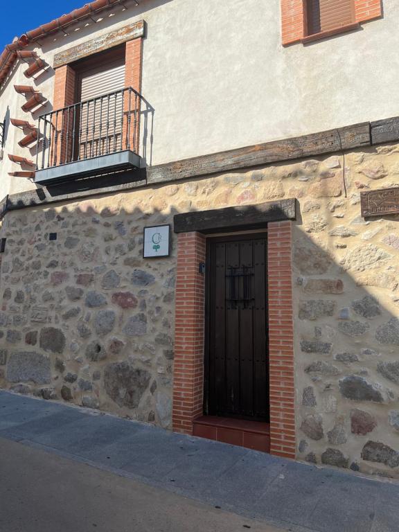 Edificio de piedra con puerta y balcón en Casa rural las pelliquerinas, en Almoharín