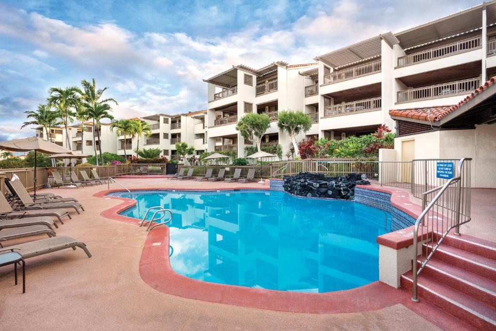 einen Pool mit Stühlen und ein Gebäude in der Unterkunft Kona Coast Resort in Kailua-Kona