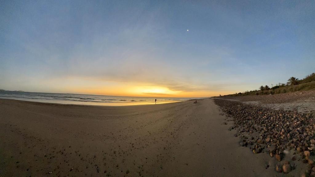 einen Strand mit Felsen und Sonnenuntergang im Hintergrund in der Unterkunft La Posada de Gogg Cabañas in Bella Vista