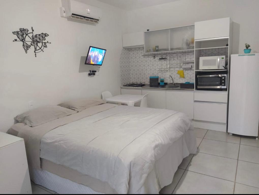 1 dormitorio blanco con 1 cama y cocina en Pousada Pontal Jurerê, en Florianópolis