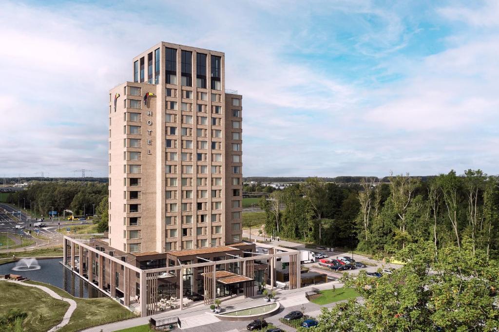 een hoog gebouw met een parkeerplaats ervoor bij Van der Valk Hotel Lelystad in Lelystad