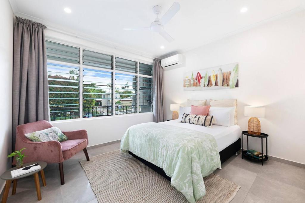 a bedroom with a bed and a chair and a window at 'Botanica Aguila' Chic Nightcliff Balcony Pad in Nightcliff