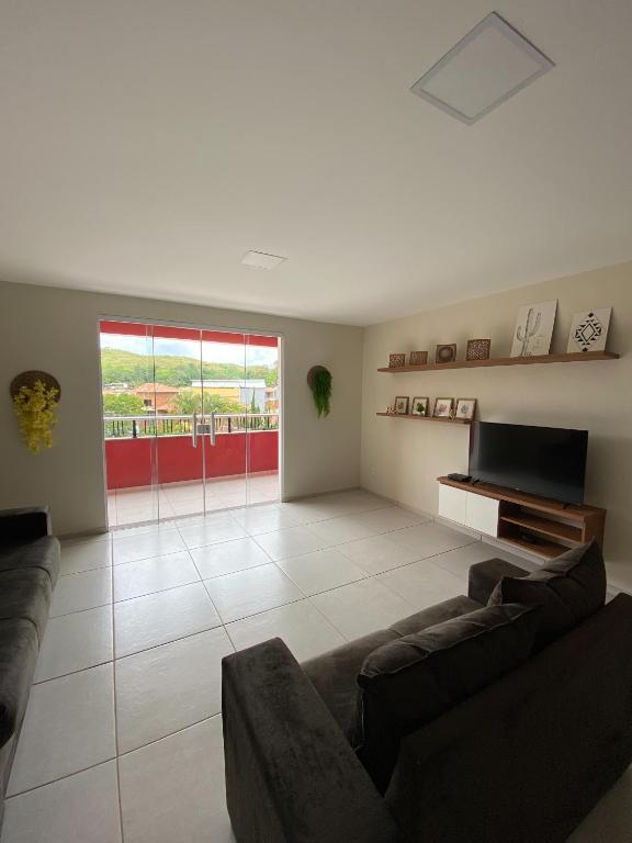 a living room with a couch and a television at Ap 2 quartos, novo, em Ipiabas in Barra do Piraí