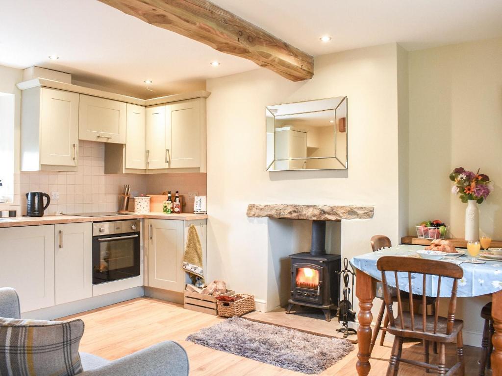 a kitchen with a table and a stove in a room at High Dale Cottage in Bellerby