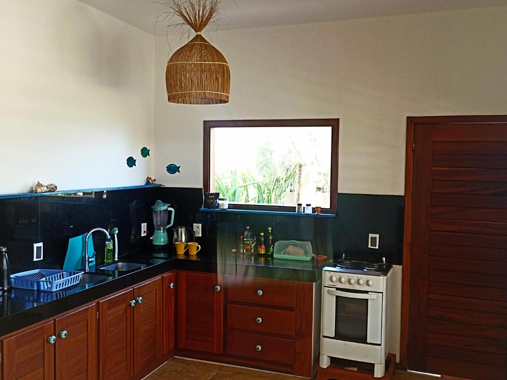 uma cozinha com um lavatório, um fogão e uma janela em Casa do Capitao em Guajiru