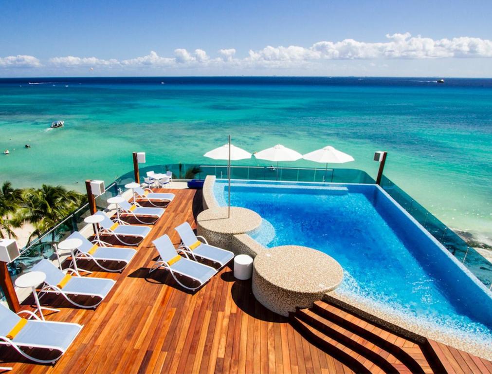 un complejo con piscina, sillas y el océano en The Carmen Hotel - Ocean Front en Playa del Carmen